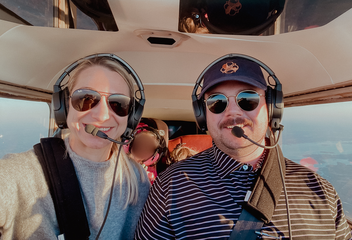 Woman and man with headsets and sunglasses on in a small airplane.