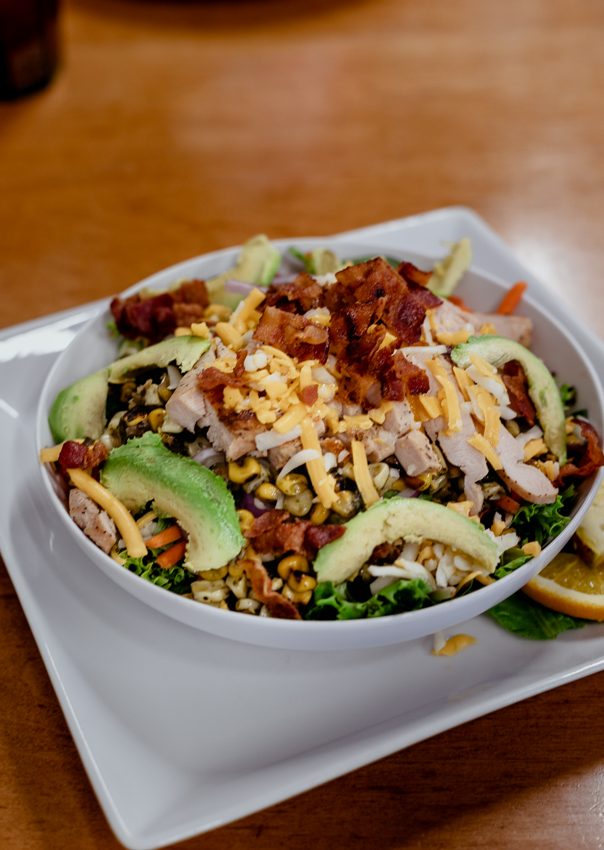 salad with chicken, corn, bacon cheese and avocado in a white bowl at shelby's diner.
